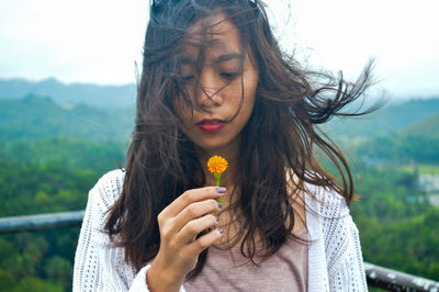 Young woman with tousled hair holding flower