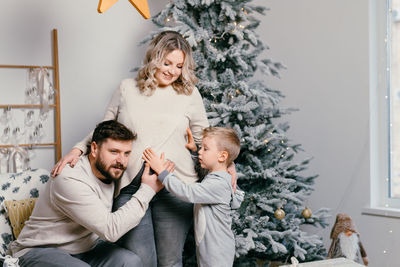 Cheerful family sitting by christmas tree