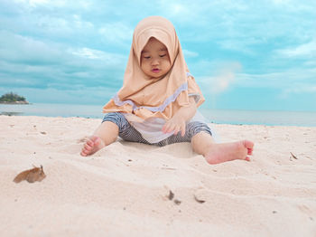 Little girl playing in the sand by the beach