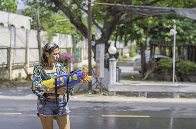 Young woman playing with squirt gun on road