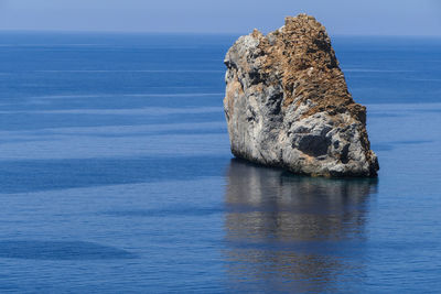 Rock formation in sea against sky