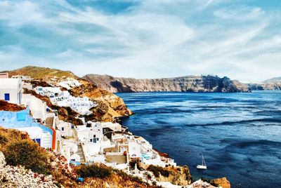 Scenic view of town by sea against sky