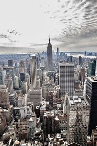 Aerial view of buildings in city against cloudy sky