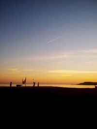 Silhouette people on landscape against sky during sunset