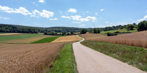 Road amidst field against sky