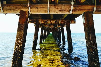 Low angle view of pier over sea against sky