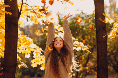 Portrait of young woman standing against trees