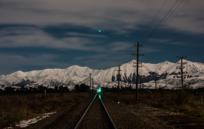 Railroad tracks leading towards mountains against sky