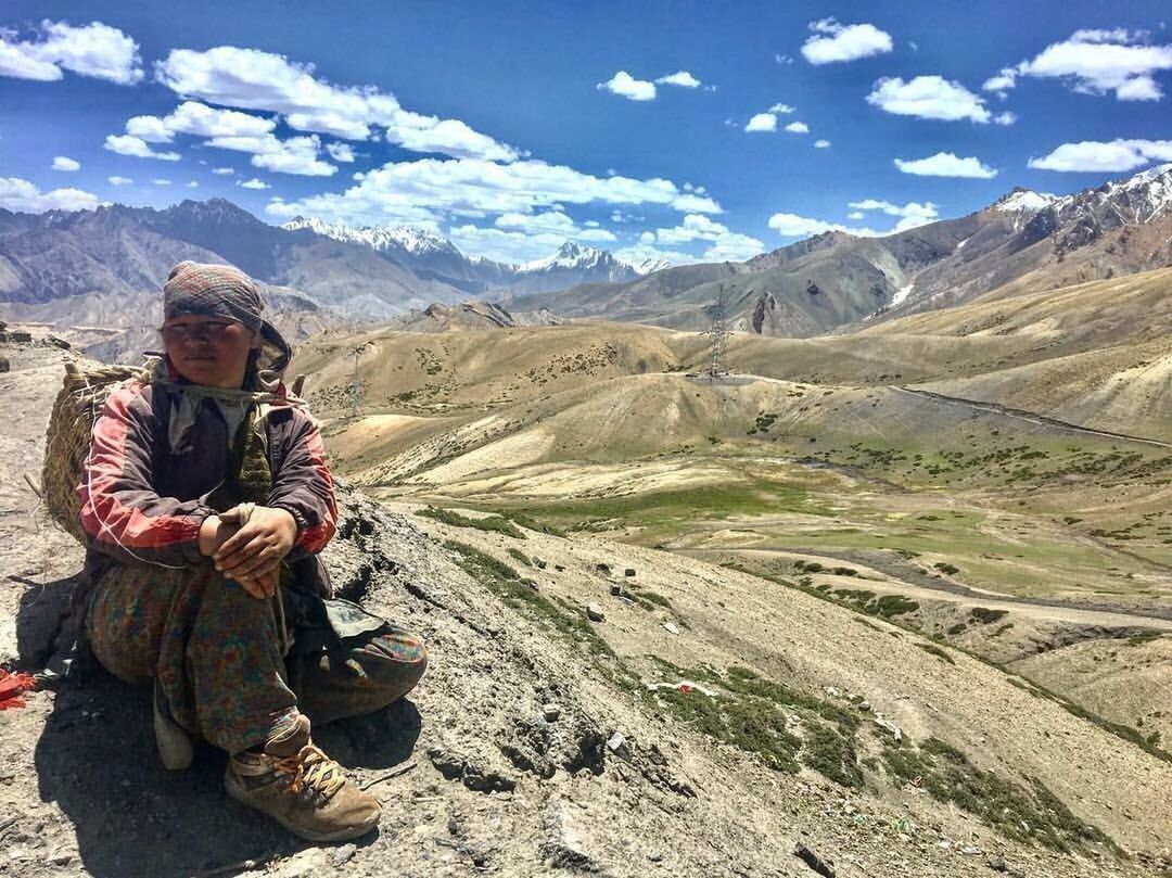 WOMAN SITTING ON MOUNTAIN ROAD