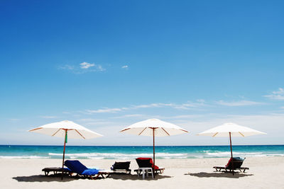 Deck chairs on beach against sky