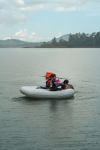 People in boat on shore against sky