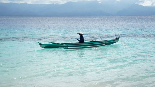 Man in boat on sea against mountains