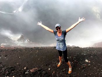 Woman standing with arms outstretched at volcanic crater