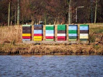 Multi colored beehives on field by lake