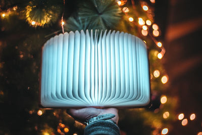 Close-up of hand touching illuminated lighting equipment at night