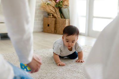 Midsection of man by son crawling on carpet