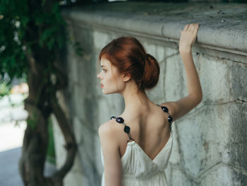 Young woman looking away while standing outdoors