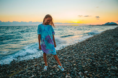 Full length of woman standing at beach against sky during sunset