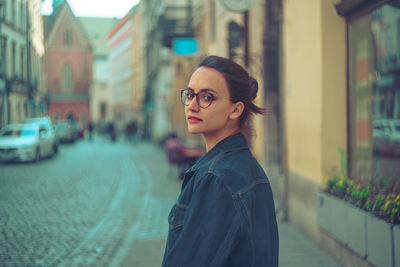 Portrait of young woman standing on street in city