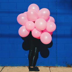 Person holding pink balloons in front of face
