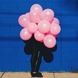 Person holding pink balloons in front of face