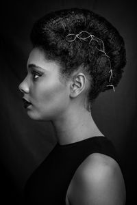 Close-up of young woman over black background