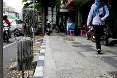 Rear view of people walking on footpath in city