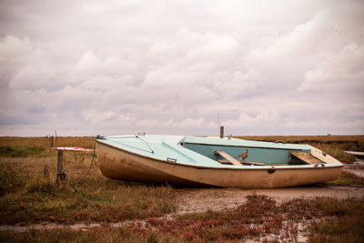 Boat moored on shore against sky