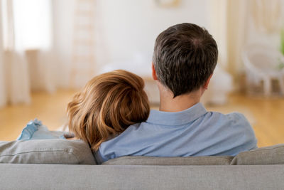 Rear view couple relaxing at home on living room couch. caucasian man and woman