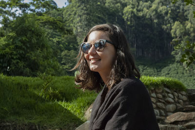 Portrait of smiling young woman against plants