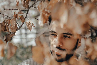 Close-up portrait of young man with autumn leaves