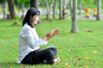 Full length of woman using mobile phone in field