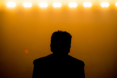 Rear view of silhouette man standing against orange sky