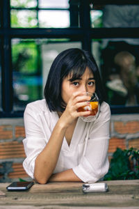 Portrait of woman drinking tea while sitting at cafe