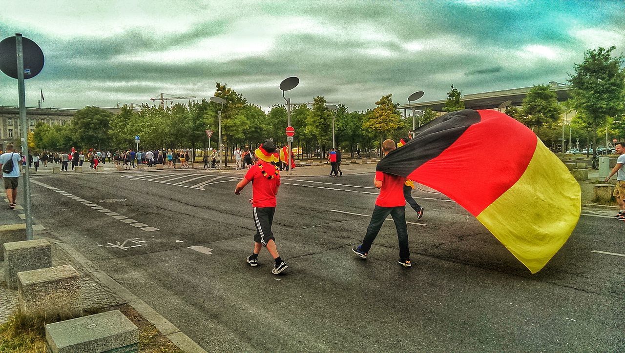 sky, leisure activity, lifestyles, cloud - sky, full length, men, childhood, cloudy, walking, tree, large group of people, person, grass, casual clothing, street, sport, boys, umbrella, togetherness