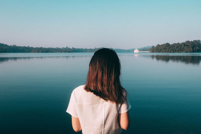 Rear view of woman standing in lake against clear sky