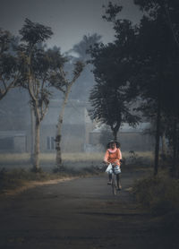 A mother wearing a cap is riding a bicycle.