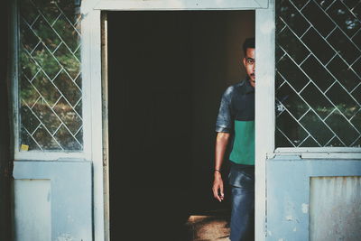 Young man looking through window