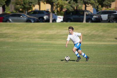 Teen soccer player training with a ball in a park