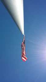 Low angle view of man flag against clear blue sky