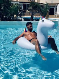 Man sitting on pool raft at swimming pool