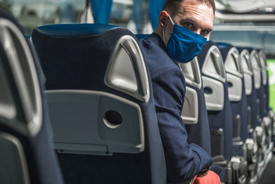 Portrait of man wearing mask sitting in bus