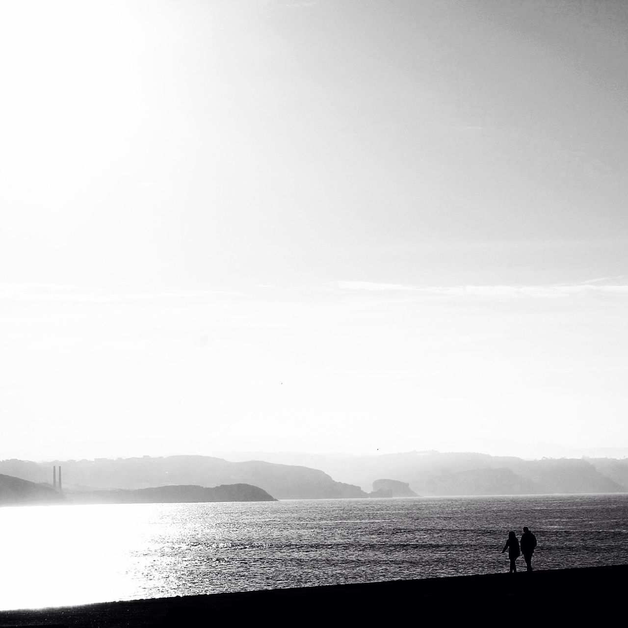 sea, water, leisure activity, lifestyles, men, copy space, scenics, tranquility, tranquil scene, silhouette, mountain, clear sky, vacations, beauty in nature, person, nature, beach, horizon over water, sky