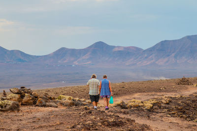 Rear view of couple on mountain against sky