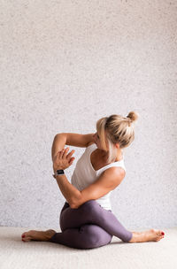 Young woman sitting on floor against wall