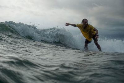 Man surfing in sea against sky