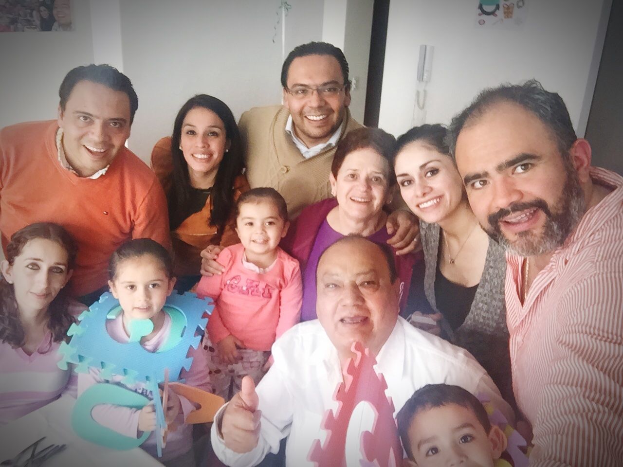 medium group of people, happiness, smiling, looking at camera, togetherness, casual clothing, mid adult men, home interior, boys, indoors, portrait, mature adult, real people, mature men, front view, senior adult, senior men, mid adult, sitting, mature women, senior women, lifestyles, grandfather, men, girls, standing, enjoyment, childhood, young men, love, fun, young adult, father, son, cheerful, celebration, bonding, eyeglasses, young women, granddaughter, day, women, friendship, adult, people