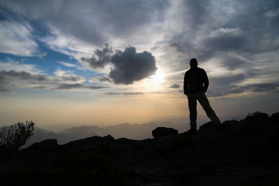 Rear view of man standing on mountain landscape against sky