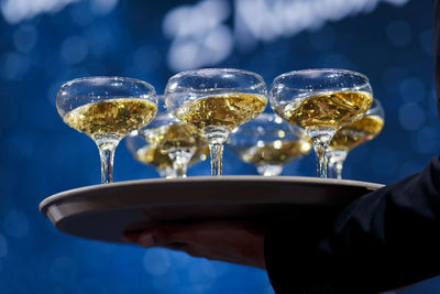 Cropped image of hand holding wineglasses in tray