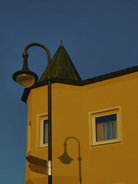 Low angle view of yellow building against clear blue sky